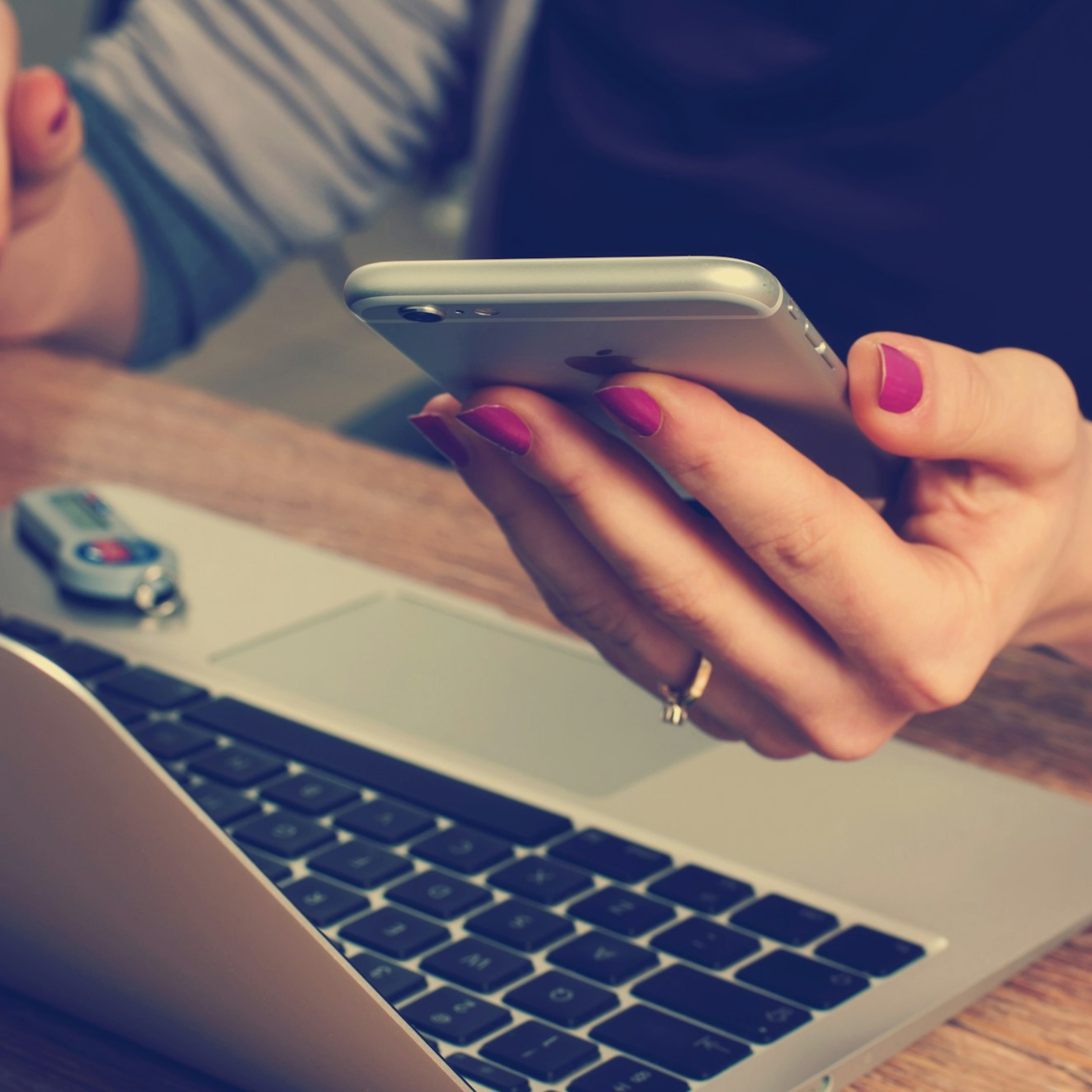 lady on laptop with mobile phone in her hand